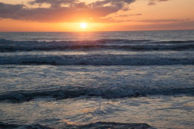 Dalgalarla okyanusun üzerinde gün doğumu