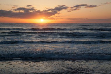 Dalgalarla okyanusun üzerinde gün doğumu