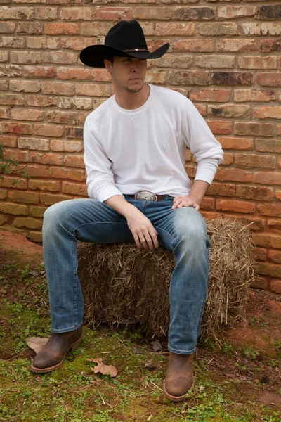 カウボーイは干し草の玉の上に座っている — ストック写真