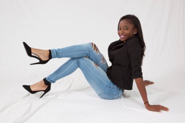 Gülümseyerek yerde oturan mutlu siyah kadın