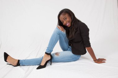 Gülümseyerek yerde oturan mutlu siyah kadın