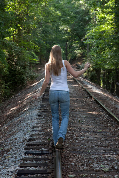 Lovely blond walking away down the railroad tracks