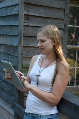 Düşünceli sarışın kadın bilgisayar tabletiyle dışarıda.