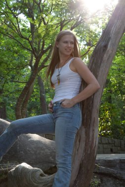 Güzel sarışın, açık havada, gülüşü ve ağacı olan.