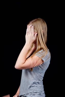 Güzel sarışın yüzünü eliyle kapatıyor.
