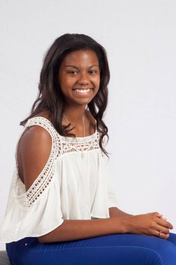 Güzel siyah kadın mutlu bir gülümsemeyle oturuyor.