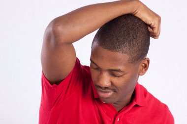 Kırmızı gömlekli mutlu siyah adam. Eli başının üstünde.