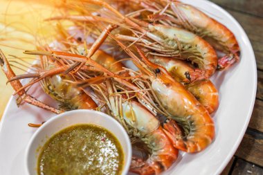 Tabakta ızgara karides ve deniz ürünleri sosu.