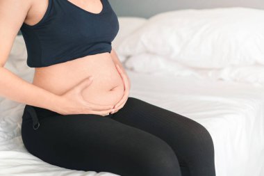 Genç hamile kadın karnına dokunuyor, hamile karnında bebeği tutuyor, erken gebelik bakımı, doğum öncesi bakım ve kadın hamileliği konsepti..