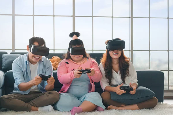 Happy asian family sitting on carpet and playing video games with VR Headset, with their daughter down syndrome child in living room, Activity happy family lifestyle virtual reality goggles concept.