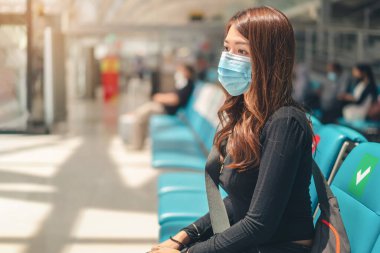 Tıbbi koruyucu yüz maskesi takan Asyalı kadın Bench 'te havaalanı, sağlık ve enfeksiyon konseptinde seyahat için bekliyor..