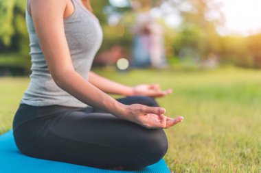 Asyalı kadın meditasyon yapıyor ve lotusta oturuyor. Parkta poz veriyor, Sağlıklı ve Yoga Kavramı, Zihin-Vücut Geliştirme Konsepti, Seçici Odaklanma, Boşluğu Kopyalama.