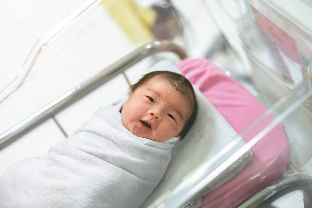 Asian newborn baby in  bassinet at delivery room at hospital.