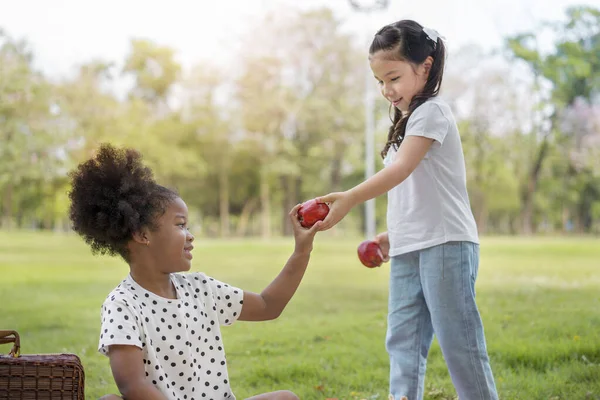 Blanke Mix Meisje Overhandigen Appel Aan Afrikaans Meisje Openlucht Park — Stockfoto