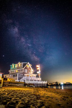 Samanyolu Galaksisi okyanus kıyısındaki güzel sahil evinin üstünde..