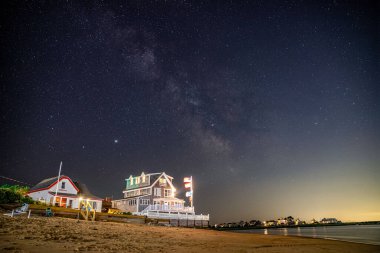 Samanyolu Galaksisi okyanus kıyısındaki güzel sahil evinin üstünde..
