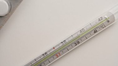 Termometre haplarla birlikte masanın üzerinde duruyor. Sıcaklık. Hastalık. Covid 19.