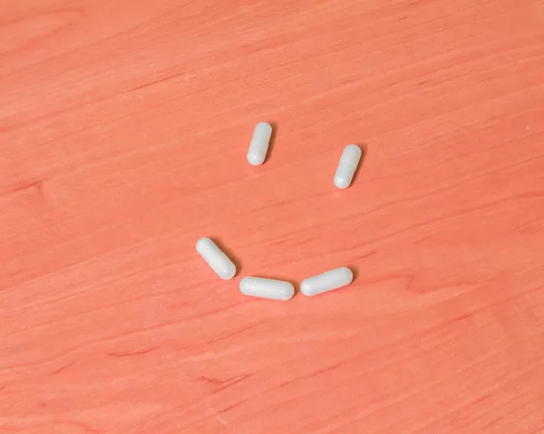 Tabletter leenden på ett träbord — Stockfoto