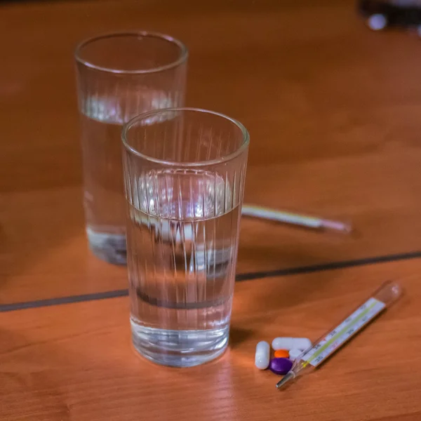 Termômetro, comprimidos e vidro de água — Fotografia de Stock