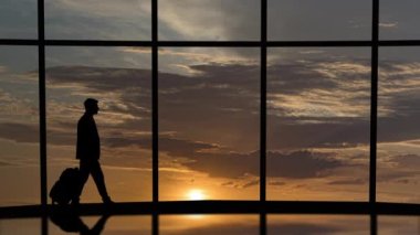 Bavullu işadamı gökyüzü manzaralı arka planda pencerenin yanında yürüyor.