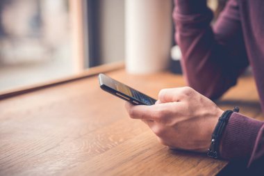 Adam pencerenin yanında bir telefon tutuyor.