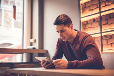 Restoran masasında tabletle oturan adam.