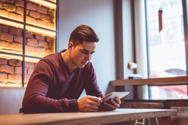 Restoran masasında tabletle oturan adam.