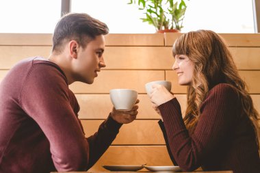 Çekici çift kafe masasında kahve içiyor.