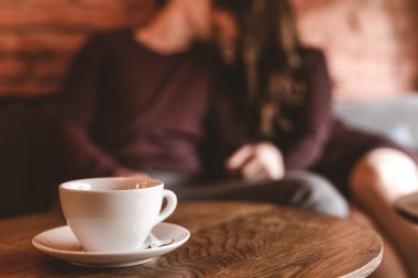 Öpüşen çiftin arka planındaki kahve fincanı.