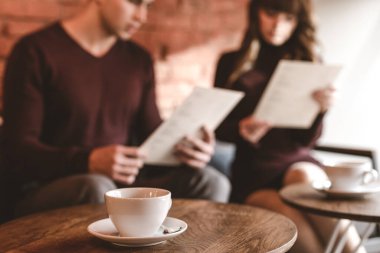 Oturan çiftin arka planındaki kahve fincanı.