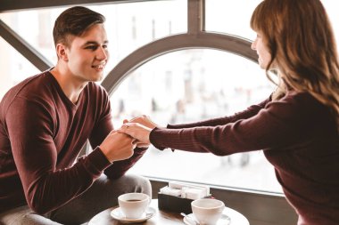 Pencerenin yanındaki restoran masasında oturan mutlu çift.