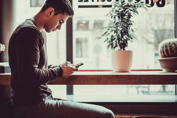 The man holding a phone at the restaurant table