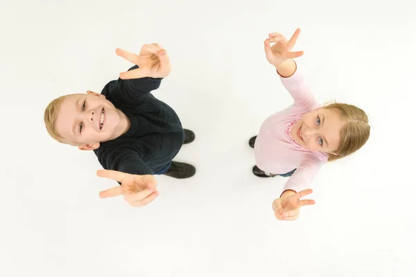 The two children show two finger on the white background. View from above