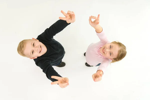 The two kids show two finger on the white background. View from above