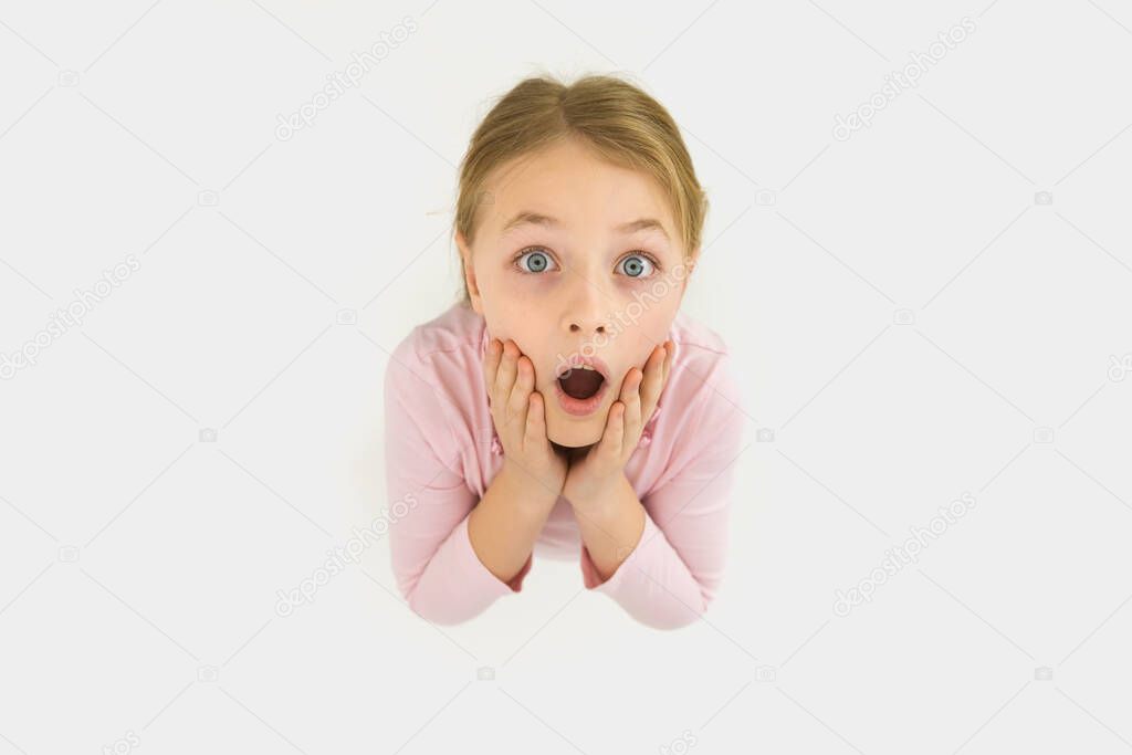 The surprised girl stand on the white background. View from above
