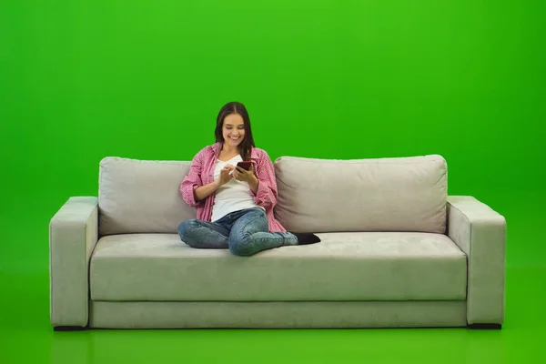 The smile woman phone on the sofa on the green background