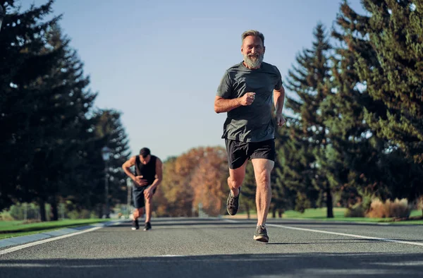 The old and young sportsmen jogging on the road