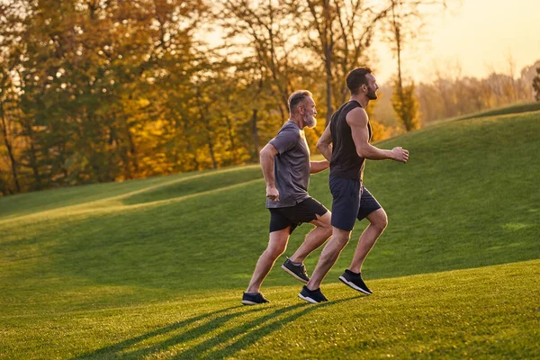 The old and young sportsmen running in the green park