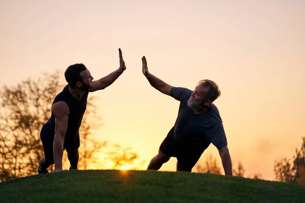 Kedua Olahragawan Mendorong Bersama Sama Pada Latar Belakang Matahari Terbenam — Stok Foto