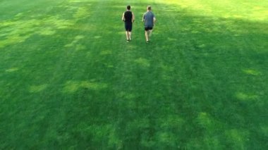 Parkta çimlerde koşan iki adam.