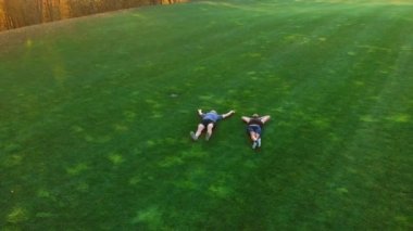 İki mutlu adam çimlerin üzerinde dinleniyor.