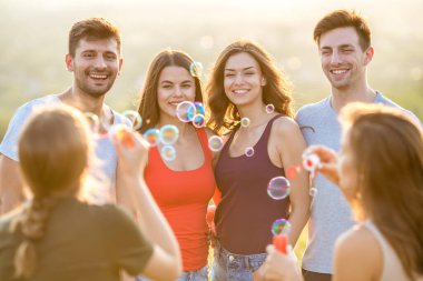 Altı mutlu insan baloncukları dışarı üflüyor.