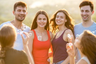 Altı mutlu insan baloncukları dışarı üflüyor.