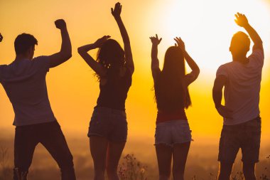 Gün batımında dans eden dört kişi.