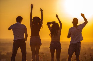 Güneşli arka planda dans eden dört kişi