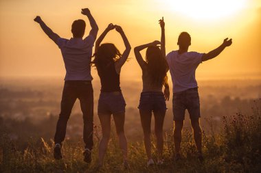 Güneşin doğuşunda dört kişi zıplıyor.
