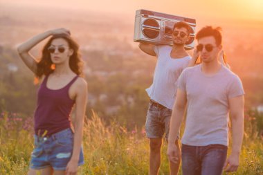 Dağın tepesinde elinde teyp olan üç genç adam.