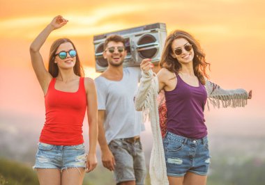 Gençler günbatımı arka planında duruyor.