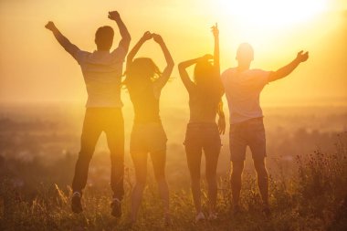 Günbatımında dört kişi zıplıyor.