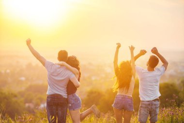 Gündoğumunun arka planında eğlenen dört kişi